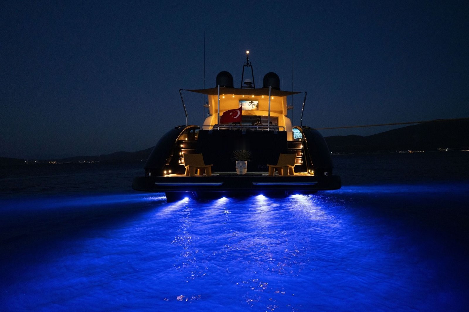 Tecnomar 116 charter Bodrum at night with underwater lights and a lit aft deck