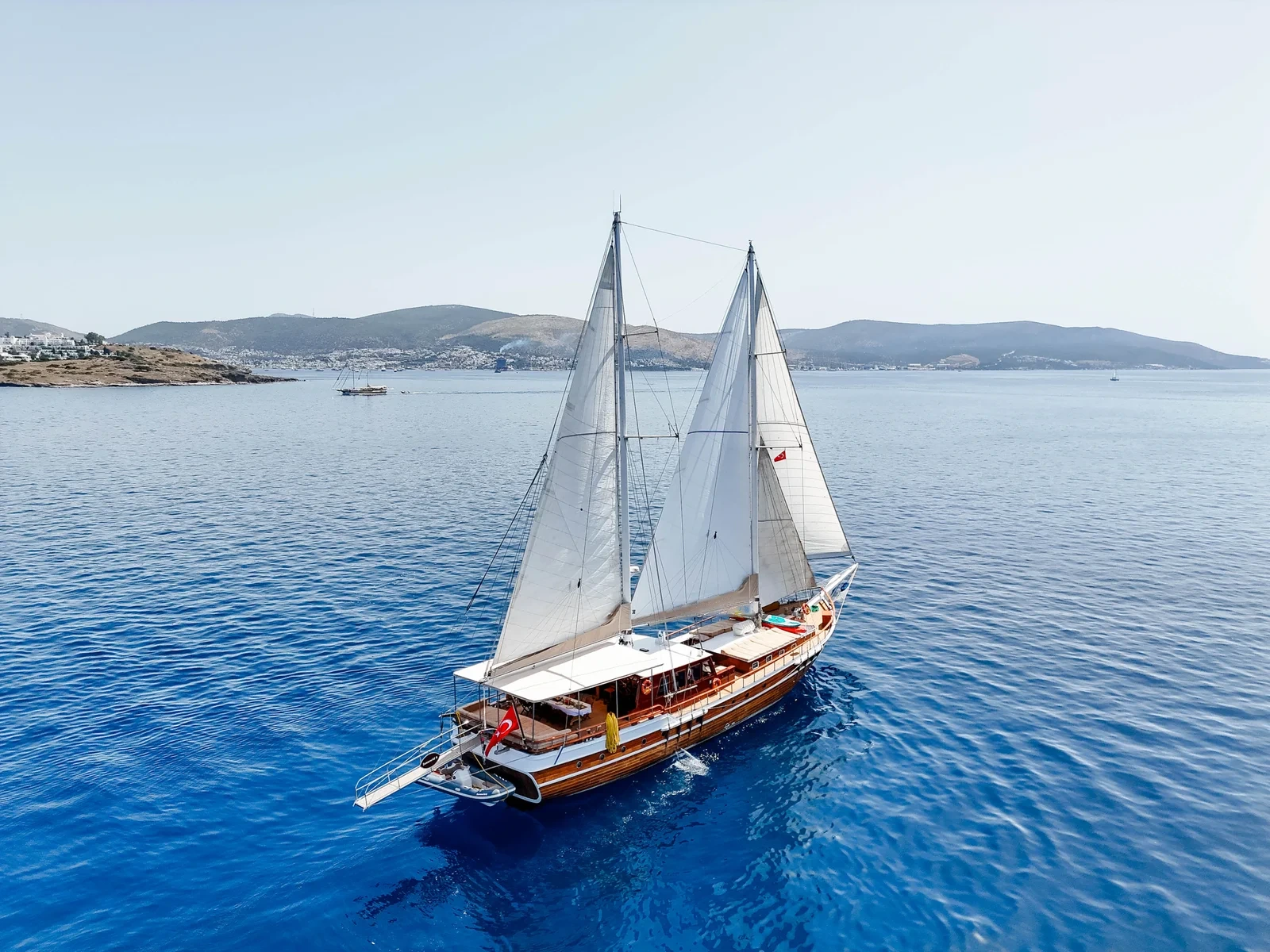 SW3001 30m traditional gulet charter Turkey under sail with Bodrum coastline behind
