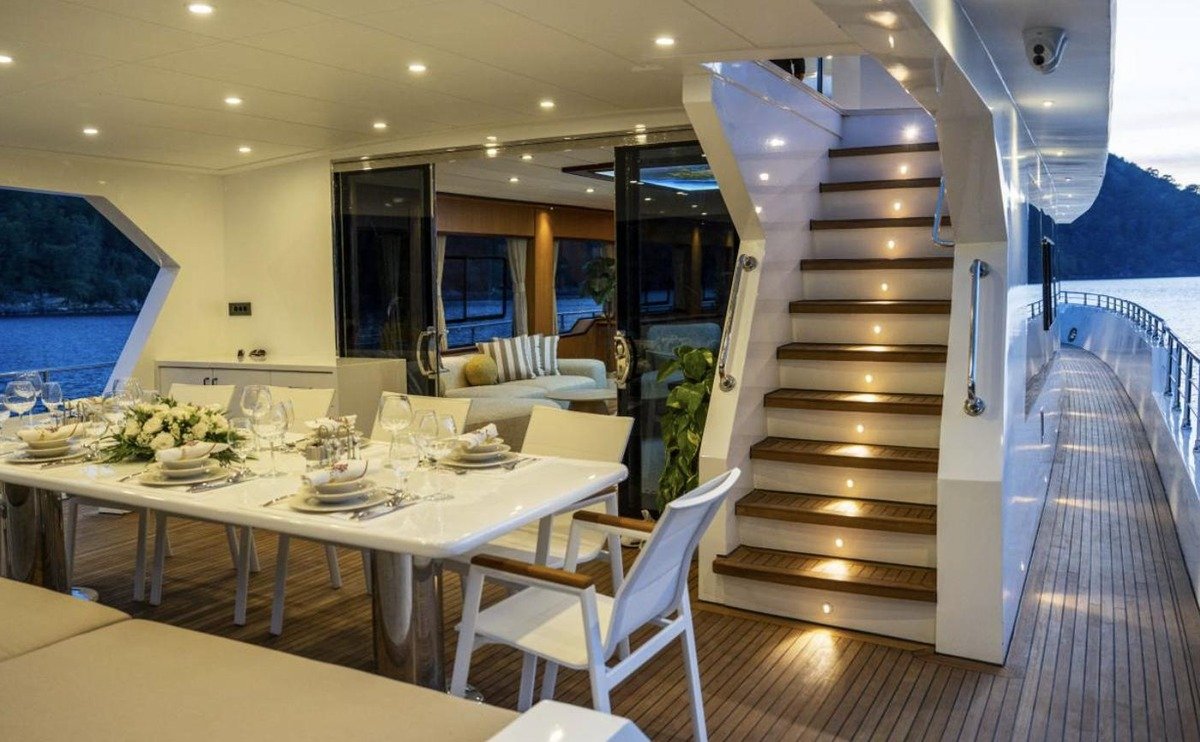 Covered aft deck dining table and staircase at dusk