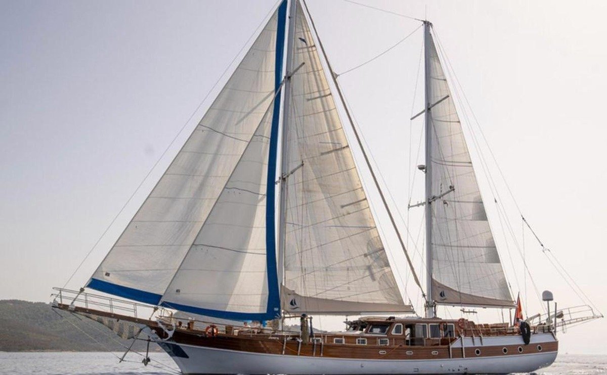 Bodrum ahşap gulet kiralama — mavi kenarlı yelkenlerle seyreden 28 metrelik gulet