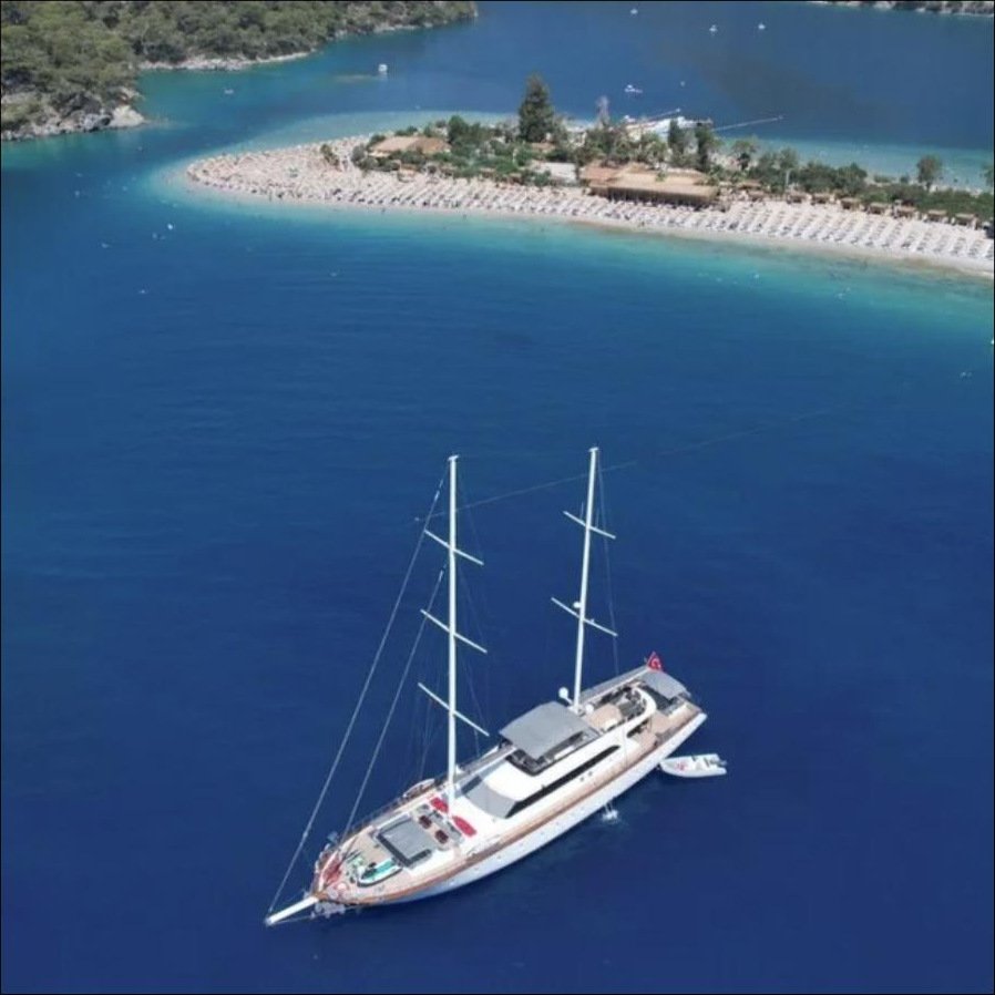 Bodrum gulet kiralama - kumsallarla çevrili bir lagün açıklarında demirli 40m guletin havadan görünümü