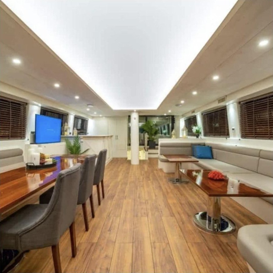 Bodrum deluxe gulet kiralama - yemek masası, oturma grubu ve ahşap zeminli ana salon