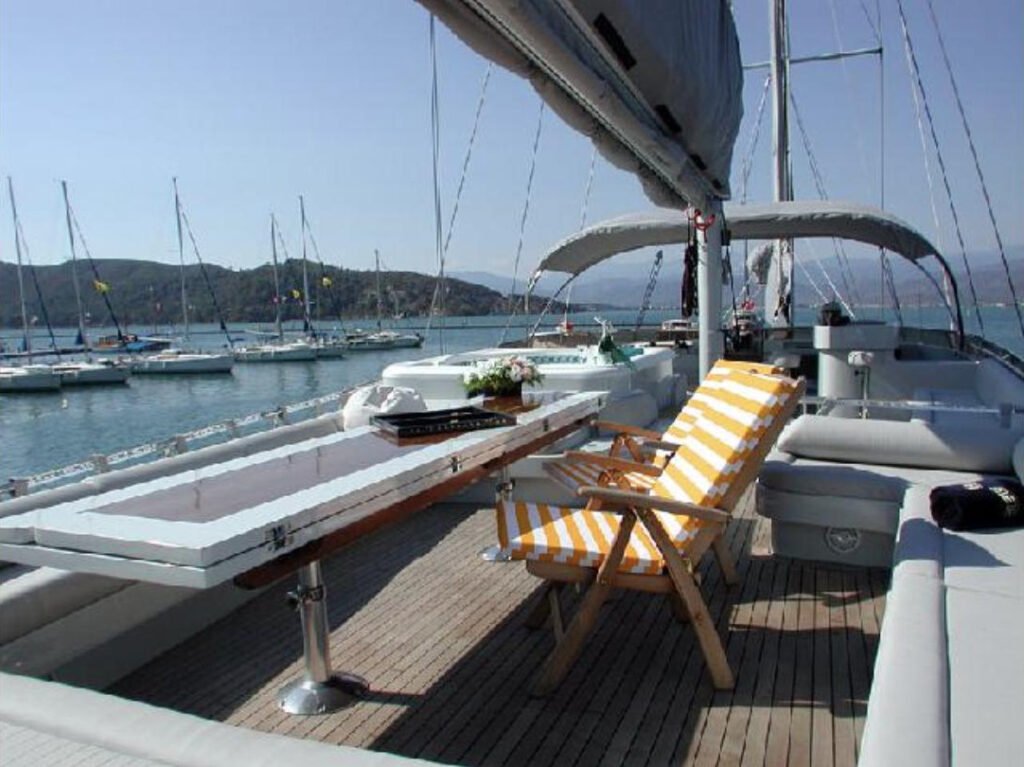 40m motor sailer'da tik masa ve güverte sandalyeleriyle gölgeli kıç güverte lounge alanı