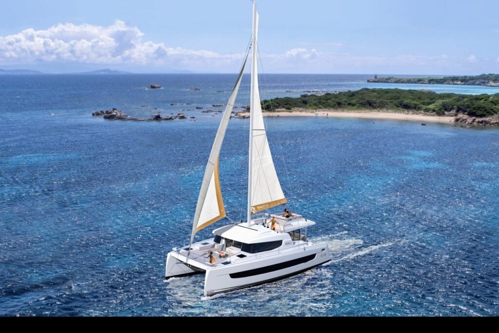 Bali 4.4 charter Ibiza – the catamaran under full sail off a Balearic beach