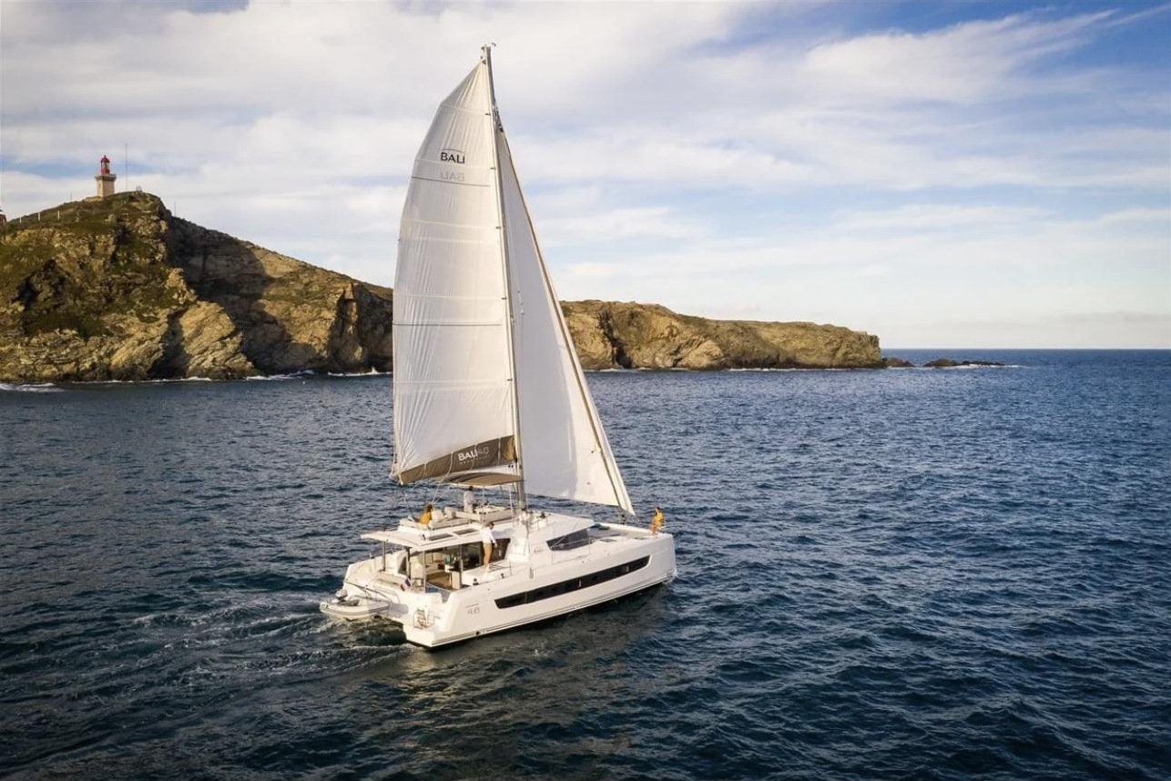 Sailing catamaran charter Fethiye cruising past a headland
