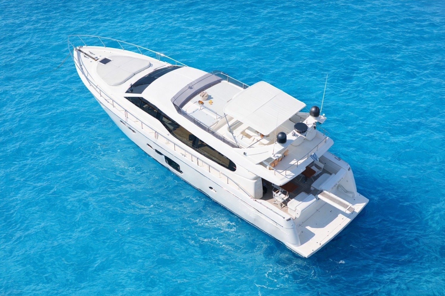 Aerial view of a Ferretti 630 motor yacht charter Mykonos at anchor in clear Aegean water