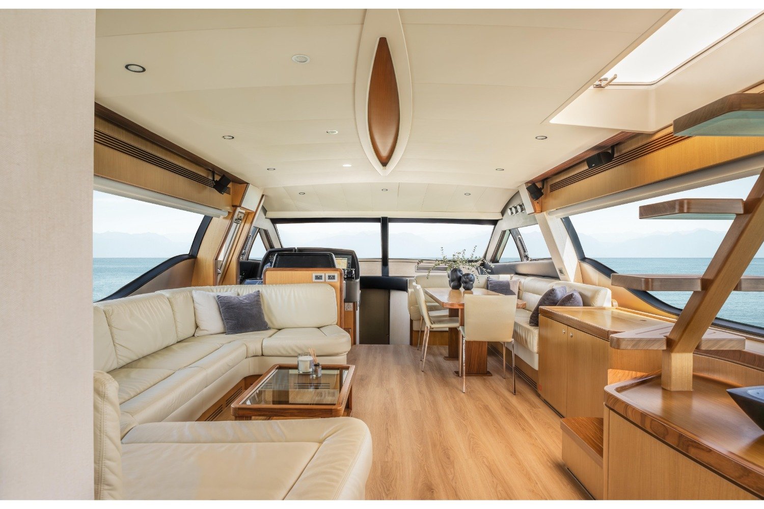 Main saloon of a Ferretti 630 motor yacht charter Mykonos with cream seating and cherry joinery
