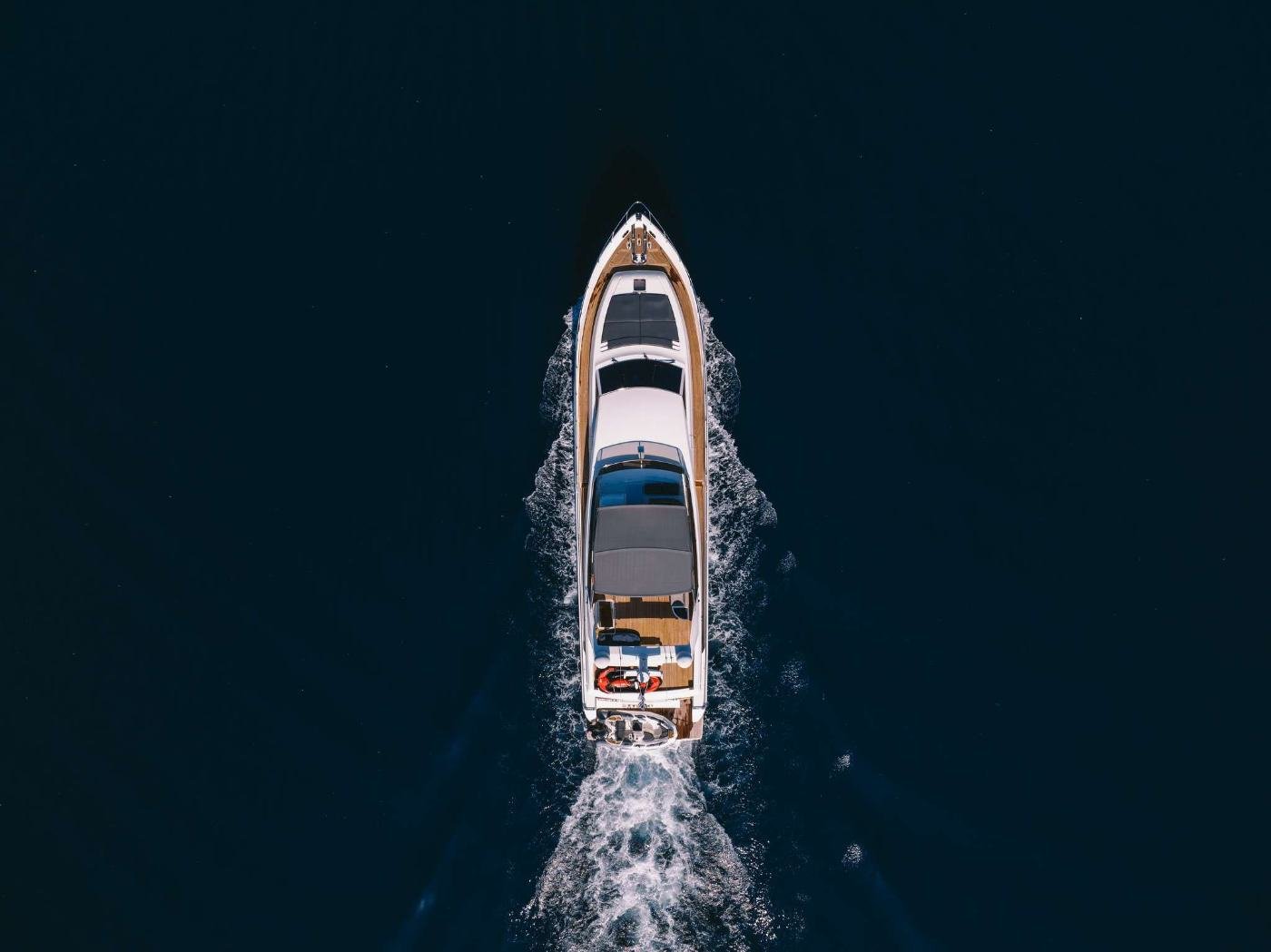 Koyu mavi sularda seyreden Mikonos kiralık Ferretti 80 flybridge yatın tepeden görünümü