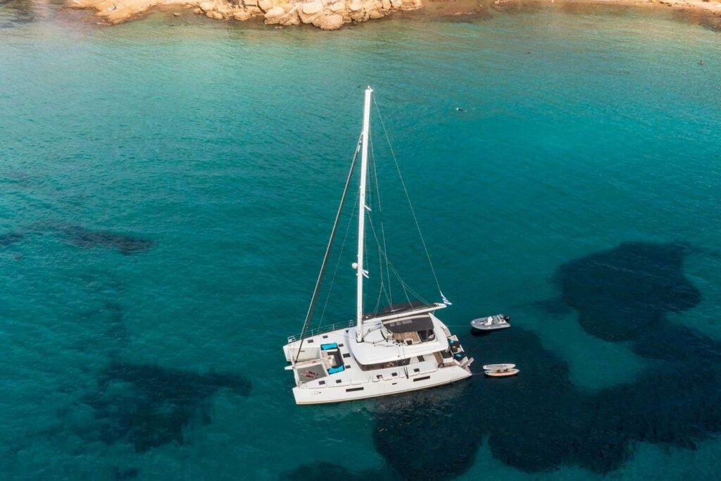 Lagoon 560 charter Athens – aerial of the crewed catamaran at anchor in a Saronic cove