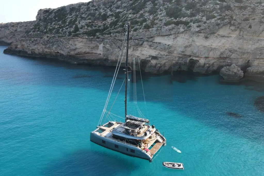 Sunreef 60 charter Ibiza – aerial view of the crewed catamaran at anchor in a turquoise Balearic cove