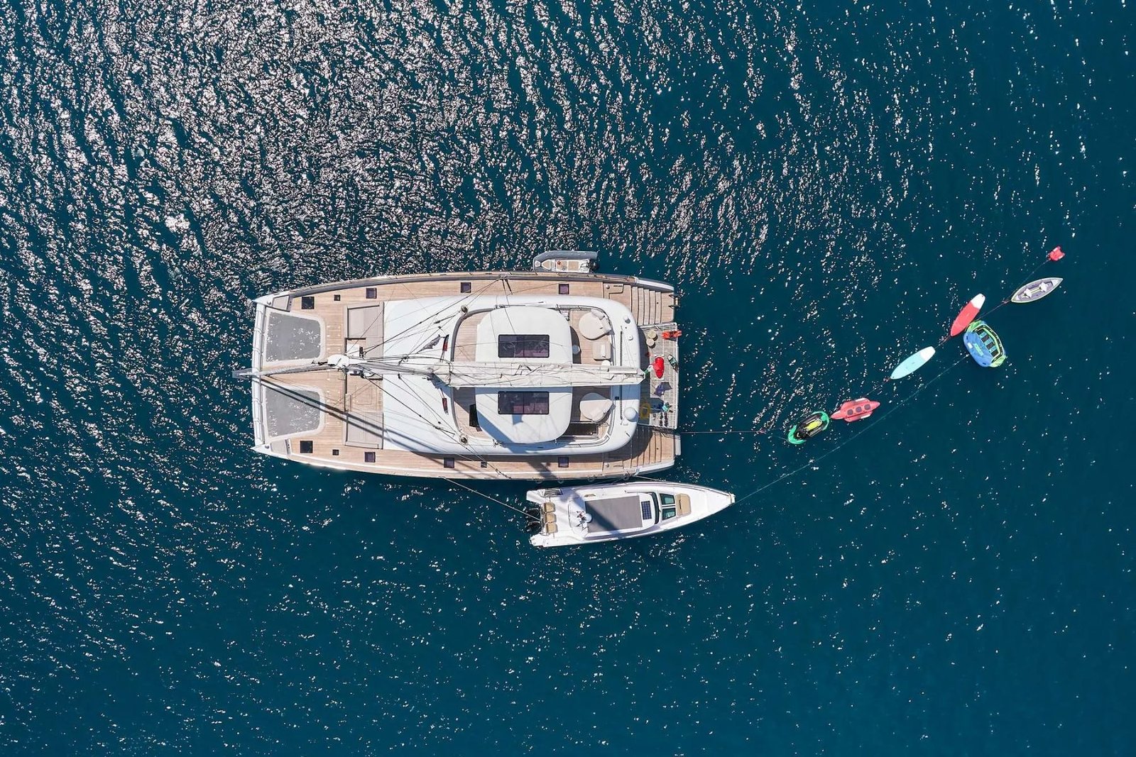 Deniz oyuncakları suya indirilmiş hâlde demirli Atina kiralık Sunreef 80 katamaranın havadan görünümü