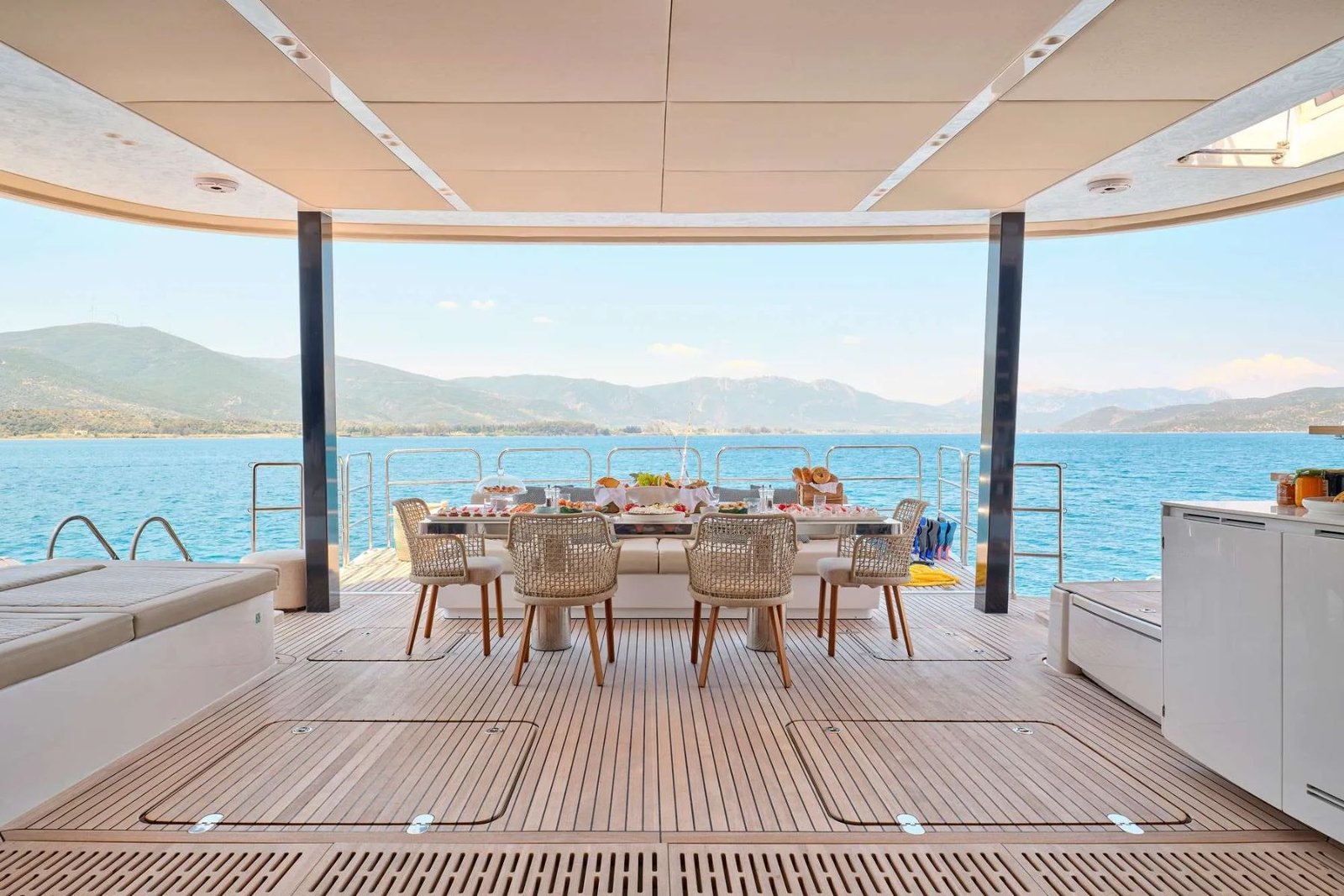 Atina kiralık Sunreef 80 katamaranda sert tavan altında kurulmuş kıç güverte yemek masası