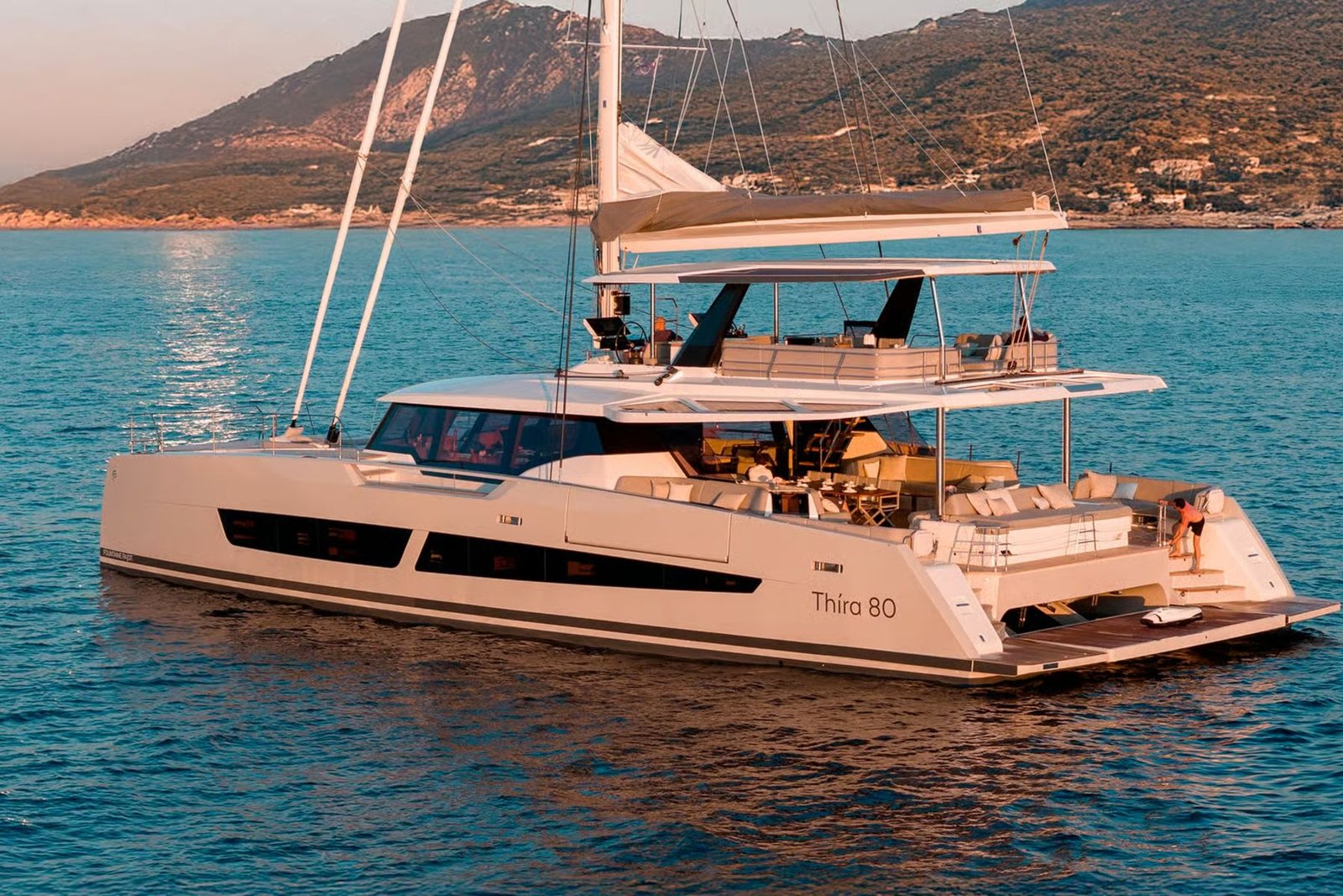 Thira 80 catamaran charter Greece stern quarter view at sunset with flybridge lit